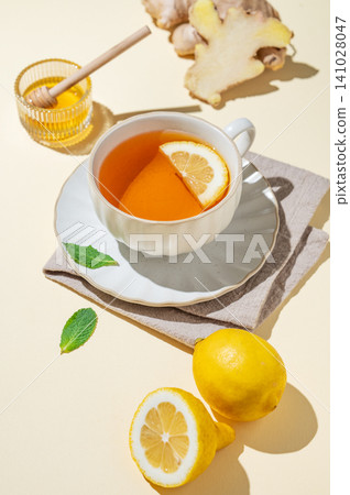 A cup of hot tea with fresh lemon, ginger, mint on a bright yellow background A cup of hot tea with fresh lemon, ginger, mint on a bright yellow background 141028047