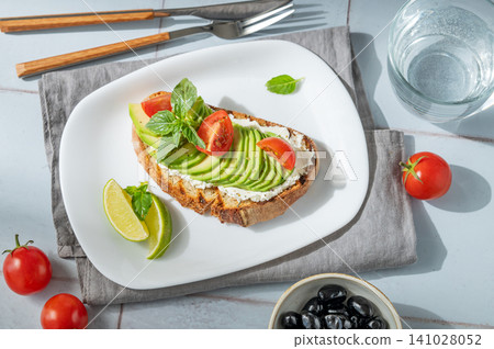 Avocado toast with cream cheese, tomatoes, and basil on a tile background Avocado toast with cream cheese, tomatoes, and basil on a tile background 141028052