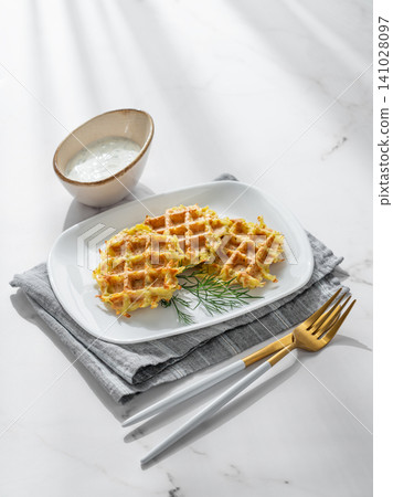 Vegetarian potato waffles with natural yogurt and dill on a plate on a marble background Vegetarian potato waffles with natural yogurt and dill on a plate on a marble background 141028097