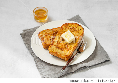 Brioche toasts with butter and honey on a plate on a concrete background Brioche toasts with butter and honey on a plate on a concrete background 141028187