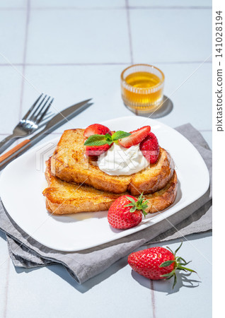 Brioche toasts with strawberries and whipped cream, drizzled with honey on a plate Brioche toasts with strawberries and whipped cream, drizzled with honey on a plate 141028194