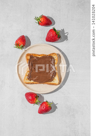 Toasted bread with chocolate cream and strawberry on a plate on a concrete background Toasted bread with chocolate cream and strawberry on a plate on a concrete background 141028204