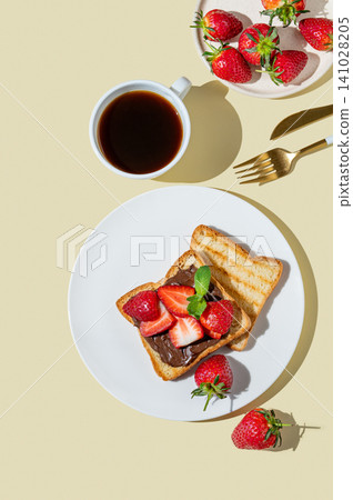Toasted bread with chocolate cream and strawberry on a white plate on a yellow background Toasted bread with chocolate cream and strawberry on a white plate on a yellow background 141028205