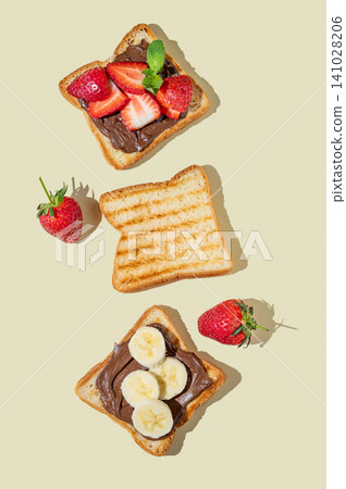 Three toasted slices with chocolate cream, strawberries, and bananas on a yellow isolated background Three toasted slices with chocolate cream, strawberries, and bananas on a yellow isolated background 141028206