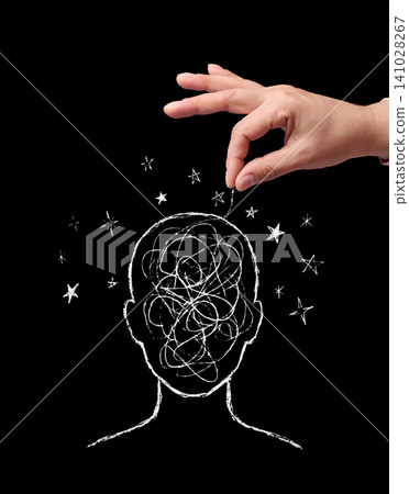A hand manipulates a thread from a drawn head with confused thoughts and stars on a black background A hand manipulates a thread from a drawn head with confused thoughts and stars on a black background 141028267