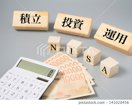 Wooden blocks and a calculator, along with money-related materials, are designed to evoke the image of the new NISA, investment plans, and asset building. Wooden blocks and a calculator, along with money-related materials, are designed to evoke the image of the new NISA, investment plans, and asset building. 141028456