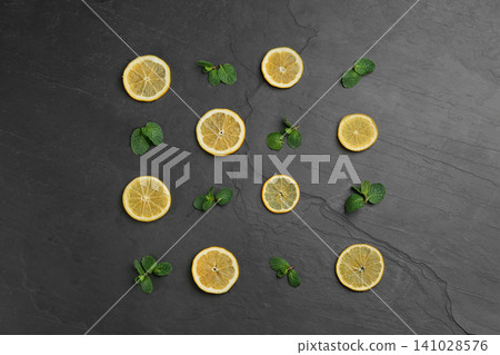 Lemonade layout with juicy lemon slices and mint on black table, top view Lemonade layout with juicy lemon slices and mint on black table, top view 141028576