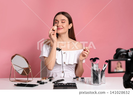 Beauty blogger recording makeup tutorial on pink background 141028632