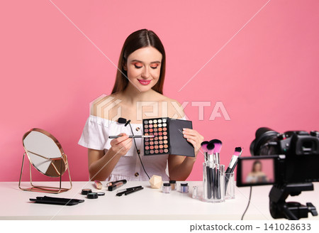 Beauty blogger recording makeup tutorial on pink background 141028633