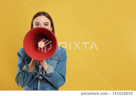 Young woman with megaphone on yellow background. Space for text Young woman with megaphone on yellow background. Space for text 141028650