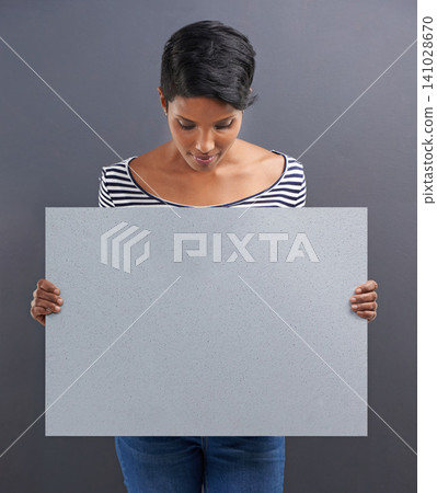 Woman, presentation and advertising with billboard for marketing on a gray studio background. Young female person or Indian holding poster or sign for notification, alert or message on mockup space Woman, presentation and advertising with billboard for marketing on a gray studio background. Young female person or Indian holding poster or sign for notification, alert or message on mockup space 141028670
