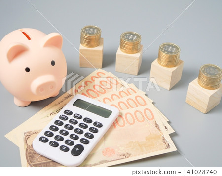 An image illustrating wealth building, household budget management, and investment using stacked coins, a calculator, banknotes, and wooden blocks (gray background, copy). 141028740