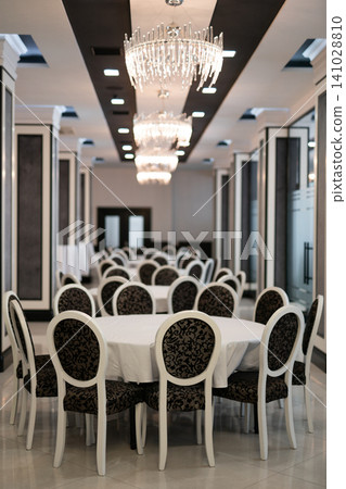 Elegant banquet hall with round tables and crystal chandeliers 141028810