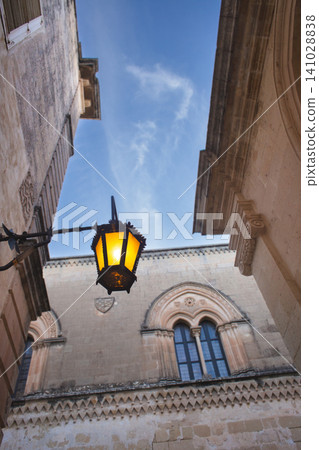 Vintage street lamp against the historic Neo-Gothic facade of Palazzo Santa Sofia in Mdina Vintage street lamp against the historic Neo-Gothic facade of Palazzo Santa Sofia in Mdina 141028838
