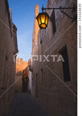 Vintage wrought iron lantern in a narrow Mdina street at twilight 141028839