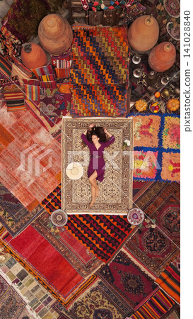 a beautiful girl in dress in a traditional turkish interior with many carpets on the wall a beautiful girl in dress in a traditional turkish interior with many carpets on the wall 141028840