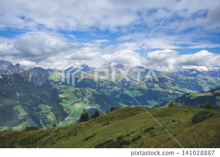 Breathtaking panoramic view of the Swiss Alps with green mountain slopes and cloudy sky 141028887
