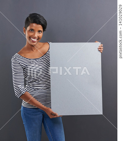 Happy woman, portrait and presentation with poster for advertising or marketing on a gray studio background. Young female person or Indian with smile, billboard or notification sign on mockup space Happy woman, portrait and presentation with poster for advertising or marketing on a gray studio background. Young female person or Indian with smile, billboard or notification sign on mockup space 141029029