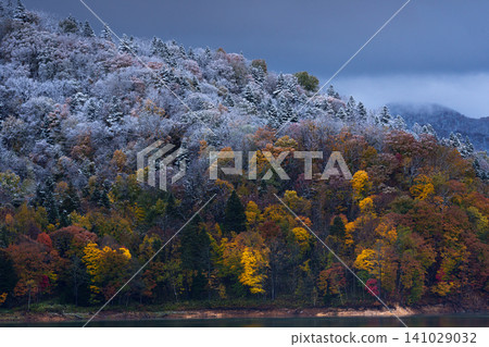 Lake Chubetsu in Hokkaido: A fantastical autumn landscape where colorful leaves and snow intertwine, visible at the foot of Mount Daisetsu. A tourist attraction. Lake Chubetsu in Hokkaido: A fantastical autumn landscape where colorful leaves and snow intertwine, visible at the foot of Mount Daisetsu. A tourist attraction. 141029032