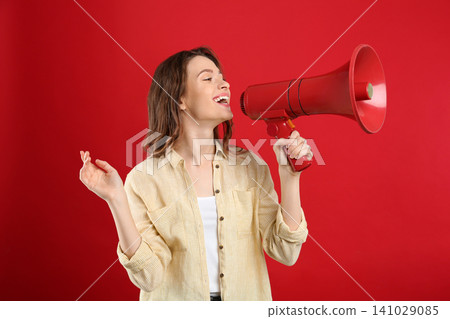 Young woman with megaphone on red background Young woman with megaphone on red background 141029085
