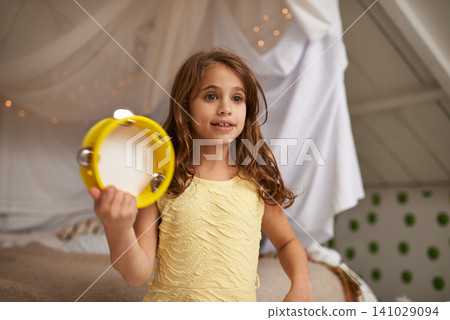 Girl, child and happy in house with tambourine for playing, music and learning rhythm in bedroom. Kid, instrument and smile for noise, sound and concert for funny games with creativity at family home 141029094