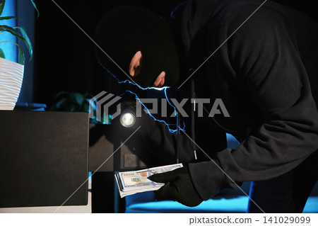 Thief taking money out of steel safe indoors at night Thief taking money out of steel safe indoors at night 141029099