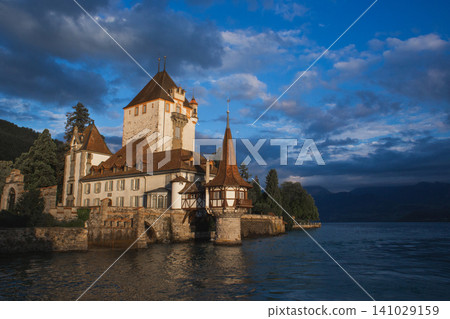 Majestic Oberhofen Castle on the shores of Lake Thun at sunset in Switzerland Majestic Oberhofen Castle on the shores of Lake Thun at sunset in Switzerland 141029159