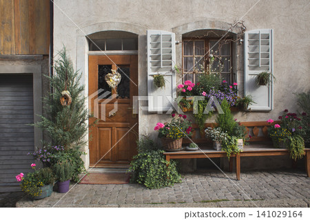 Charming entrance of a rustic European stone house with abundant flowers in potted plants Charming entrance of a rustic European stone house with abundant flowers in potted plants 141029164