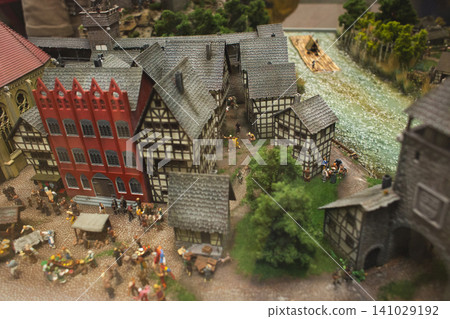 Miniature medieval town square with a bustling market and red guildhall Miniature medieval town square with a bustling market and red guildhall 141029192