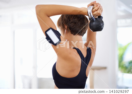 Home, gym or woman with fitness, kettlebell or music for strength training, workout or exercise. Healthy, sports or back of female person with weight or strong arms streaming podcast audio or radio 141029297