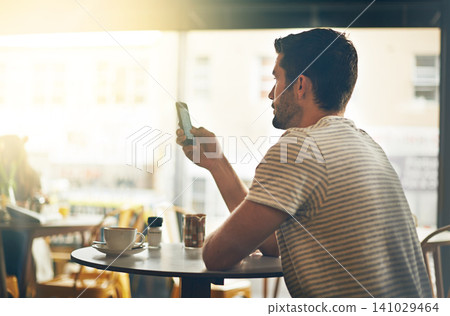Young man, typing and reading with phone at cafe in social media, communication or networking at indoor restaurant. Male person on mobile smartphone for online chatting, texting or app at coffee shop Young man, typing and reading with phone at cafe in social media, communication or networking at indoor restaurant. Male person on mobile smartphone for online chatting, texting or app at coffee shop 141029464