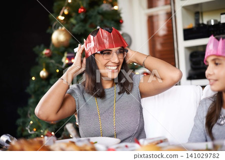 Hat, Christmas and mom with daughter at table for festive bonding, smile and eating together in home. Holiday, celebration and happy mother with food, child xmas dinner tradition with family at tree Hat, Christmas and mom with daughter at table for festive bonding, smile and eating together in home. Holiday, celebration and happy mother with food, child xmas dinner tradition with family at tree 141029782