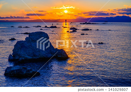 An autumn evening view from the grounds of Morito Shrine: the setting sun sinking directly above Yujiro Lighthouse, creating a shimmering path of light on the sea. An autumn evening view from the grounds of Morito Shrine: the setting sun sinking directly above Yujiro Lighthouse, creating a shimmering path of light on the sea. 141029807