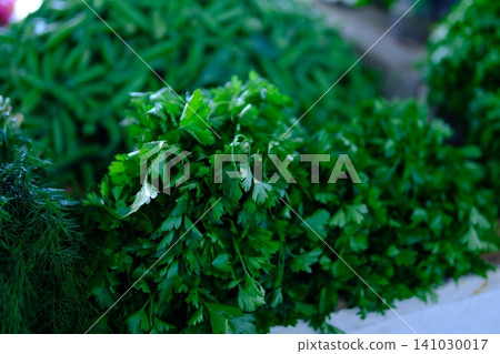 Fresh arugula parsley lettuce and mixed leafy greens displayed at farmers market with seasonal garden herbs and natural local harvest Fresh arugula parsley lettuce and mixed leafy greens displayed at farmers market with seasonal garden herbs and natural local harvest 141030017