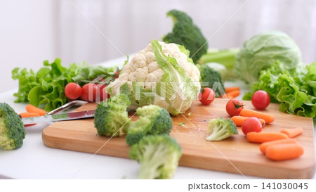 Breaking cauliflower head into pieces on rustic table with fresh garden ingredients Breaking cauliflower head into pieces on rustic table with fresh garden ingredients 141030045