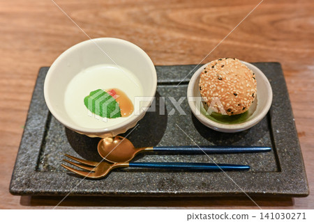 精緻的中式套餐中的開胃小點和芝麻甜點,盛放在黑色石盤中,賞心悅目。 精緻的中式套餐中的開胃小點和芝麻甜點,盛放在黑色石盤中,賞心悅目。 141030271