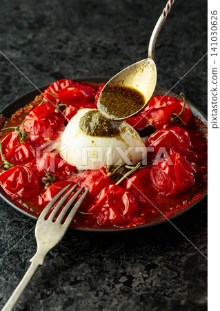 Mozzarella with pesto sauce and roasted red cherry tomatoes. 141030626