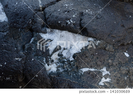 A close-up of a white quartz vein embedded in a dark porous volcanic rock surface A close-up of a white quartz vein embedded in a dark porous volcanic rock surface 141030689