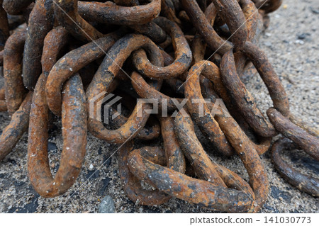 Close-up of a heavy rusty iron chain tangled in a pile on a ground Close-up of a heavy rusty iron chain tangled in a pile on a ground 141030773