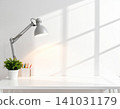 Minimalist desk workspace with lamp, potted plant, and colored pencils 141031179
