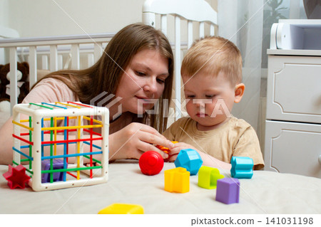 Toddler sorting colorful cubes. Logic development through play. Colorful educational toy supports natural curiosity and brain development Toddler sorting colorful cubes. Logic development through play. Colorful educational toy supports natural curiosity and brain development 141031198