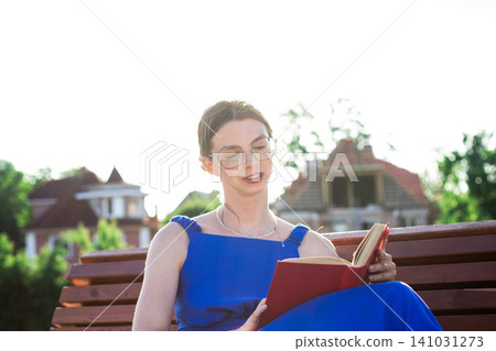 Young woman immersed in book reading. Digital detox by choice. Modern mindfulness practice outdoors on nature. Book lovers day Young woman immersed in book reading. Digital detox by choice. Modern mindfulness practice outdoors on nature. Book lovers day 141031273