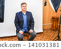 A man sits on a chair in a photo studio, preparing for a photo shoot for documents and a passport 141031381