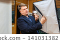 Photographer inspecting a burnt-out studio light bulb in a professional photo studio lighting fixture 141031382