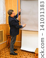 A male photographer lowers a gray paper backdrop in a professional studio 141031383