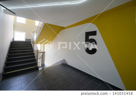 Modern apartment building staircase with bold yellow accent and floor numbering 141031458