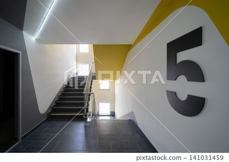Modern apartment building staircase with bold yellow accent and floor numbering Modern apartment building staircase with bold yellow accent and floor numbering 141031459