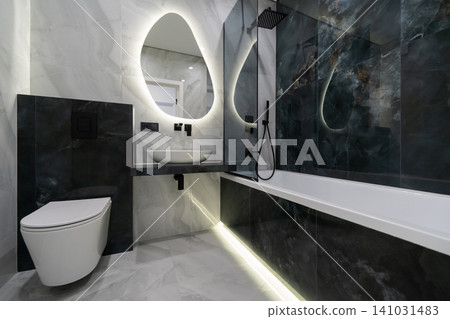 Modern luxury bathroom with black marble accents and backlit organic mirror Modern luxury bathroom with black marble accents and backlit organic mirror 141031483