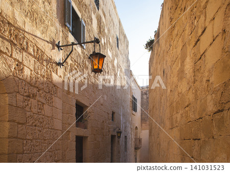 Traditional wrought iron street lantern on a limestone wall in Mdina Malta Traditional wrought iron street lantern on a limestone wall in Mdina Malta 141031523