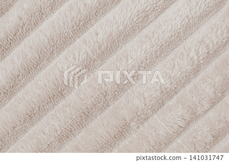 Horizontal close up flat lay shot of a cozy beige plush fleece blanket fabric texture with distinct diagonal ribbed rows of soft fluffy synthetic fur material Horizontal close up flat lay shot of a cozy beige plush fleece blanket fabric texture with distinct diagonal ribbed rows of soft fluffy synthetic fur material 141031747